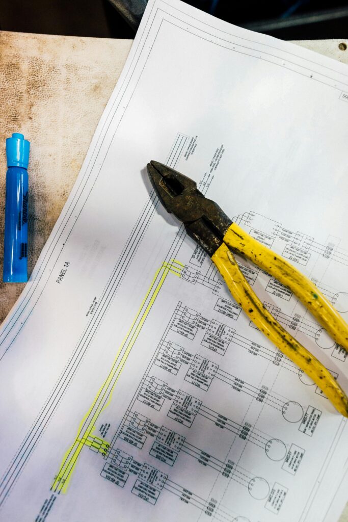 electrical design plans with a blue marker on the left and a wire cutter sitting on top of the plans