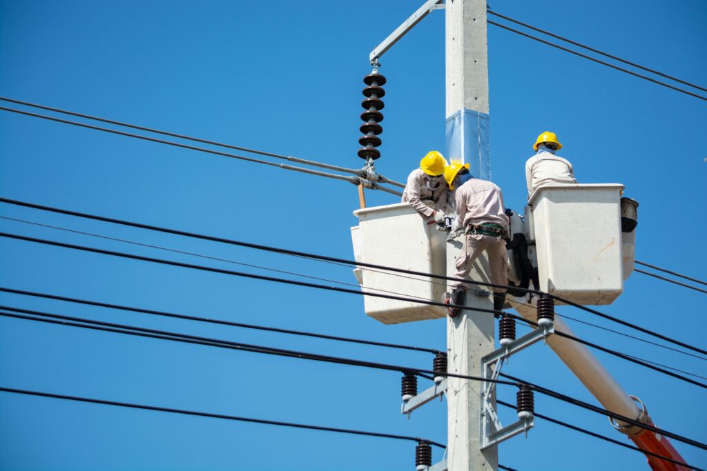 people with yellow hard hats working  in bucket on power lines